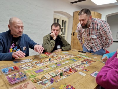 na zdjęciu osoby siedzące przy stolikach, grające w gry planszowe. Kliknij, aby powiększyć zdjęcie.